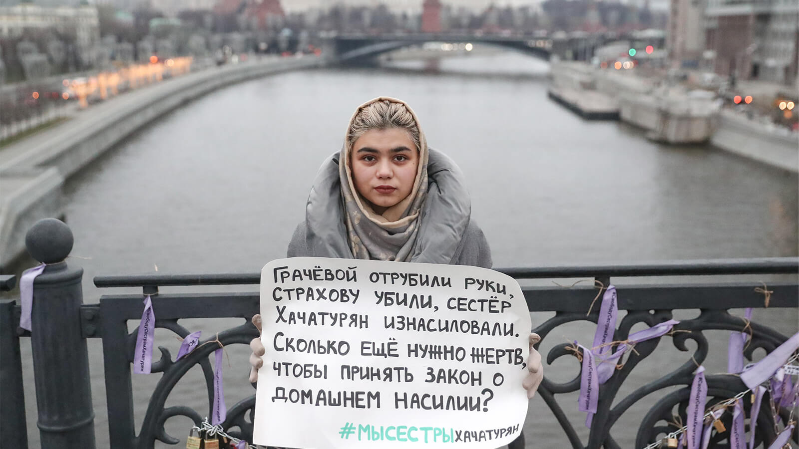 A woman holds a placard with a message reading "Gracheva had her hands cut off. Strakhova was killed. Khachaturyan sisters were raped. How many victims do we need to pass a bill on domestic violence?" during a one-person protest on Patriarshy Bridge in Moscow