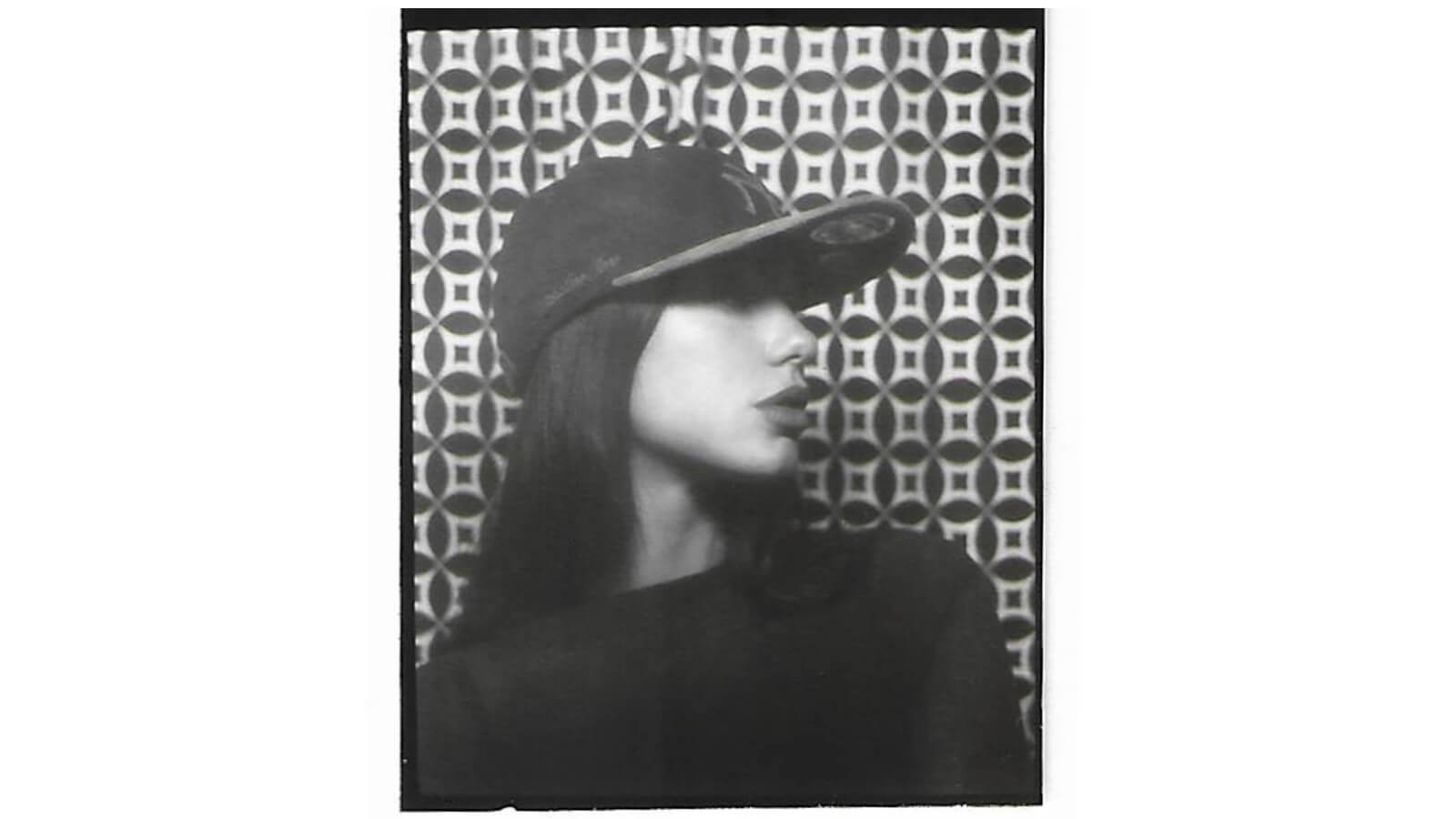 Black and white photobooth strip featuring Dua Lipa, a brunette woman wearing a baseball cap