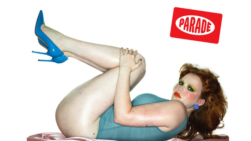 Auburn haired model lies on back wearing blue stiletto heels and blue lingerie