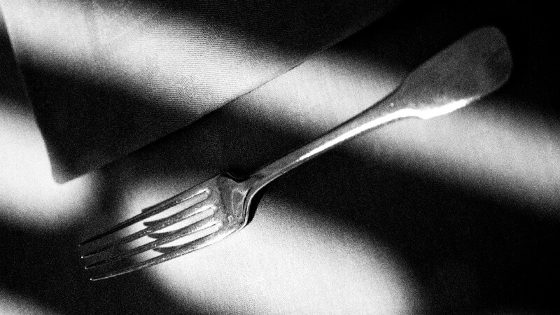 Black and white image of a fork in shadows