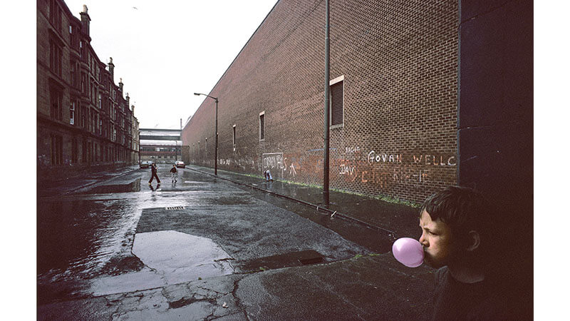 Archive image of young boy in Glasgow blowing bubblegum in the deserted street