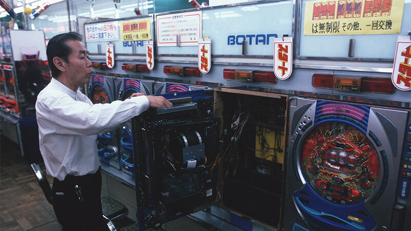 Man servicing pachinko machine in pachinko parlour, Japan