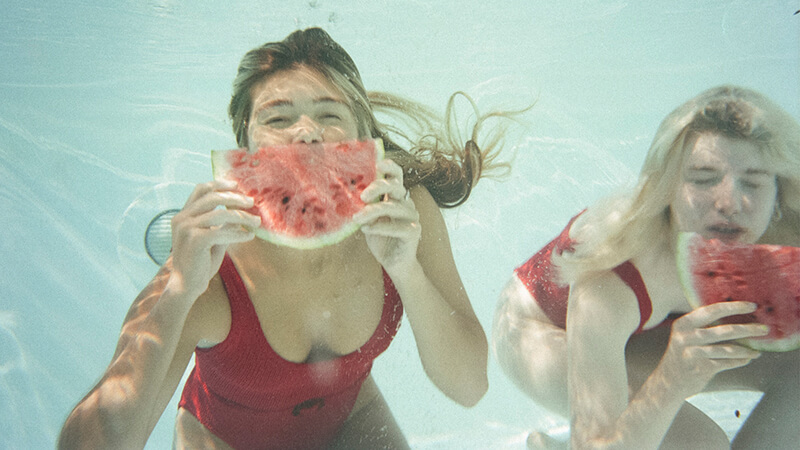 Image of two girls under water with Watermelon pieces